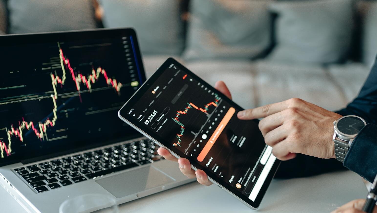 Two professionals analyzing stock graphs on digital devices in a modern business setting.